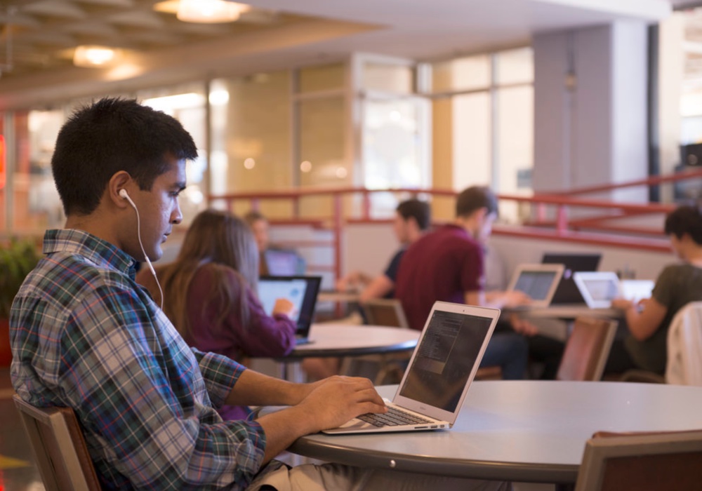 Photo of person wearing headphones using a laptop